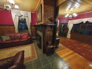 A cozy living room with a fireplace, leather sofa, and a patterned rug.