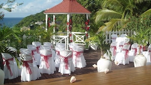 A gazebo with a red roof, surrounded by white chairs with red sashes, set against a backdrop of greenery and a view of the sea. - Sea view, fully staffed villa for Families & Retreats, groups of 9 - 20 guests (Cap Estate)