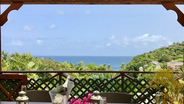 A wooden table with a view of the ocean, a bottle of champagne, and a lantern. - Sea view, fully staffed villa for Families & Retreats, groups of 9 - 20 guests (Cap Estate)