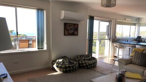 En rummelig stue med stort vindue, sofa, sofabord og puf-sækkestole.