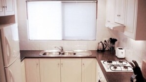 Une petite cuisine équipée d’un évier, d’une cuisinière et de placards.