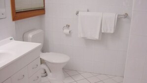 Une salle de bain équipée de toilettes, d’un lavabo et d’un porte-serviettes.