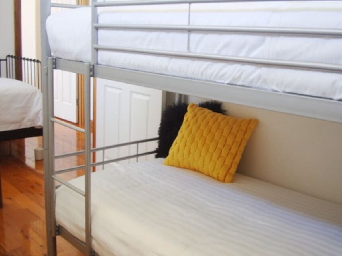 Una cama litera con un almohadón amarillo y un colchón blanco.