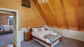 Cozy cabin bedroom with a wooden bed, bedside tables, and a lamp on each.