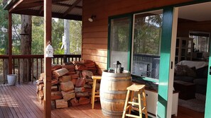 Relax on the deck with a view of the surrounding trees, featuring a cozy living area and a fireplace.