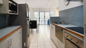 Une cuisine moderne dotée d’un four à micro-ondes encastré, d’appareils électroménagers en acier inoxydable et d’un dosseret carrelé.