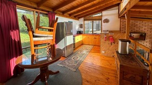A cozy cabin with a wooden interior, a dining table, a refrigerator, and a kitchen area.