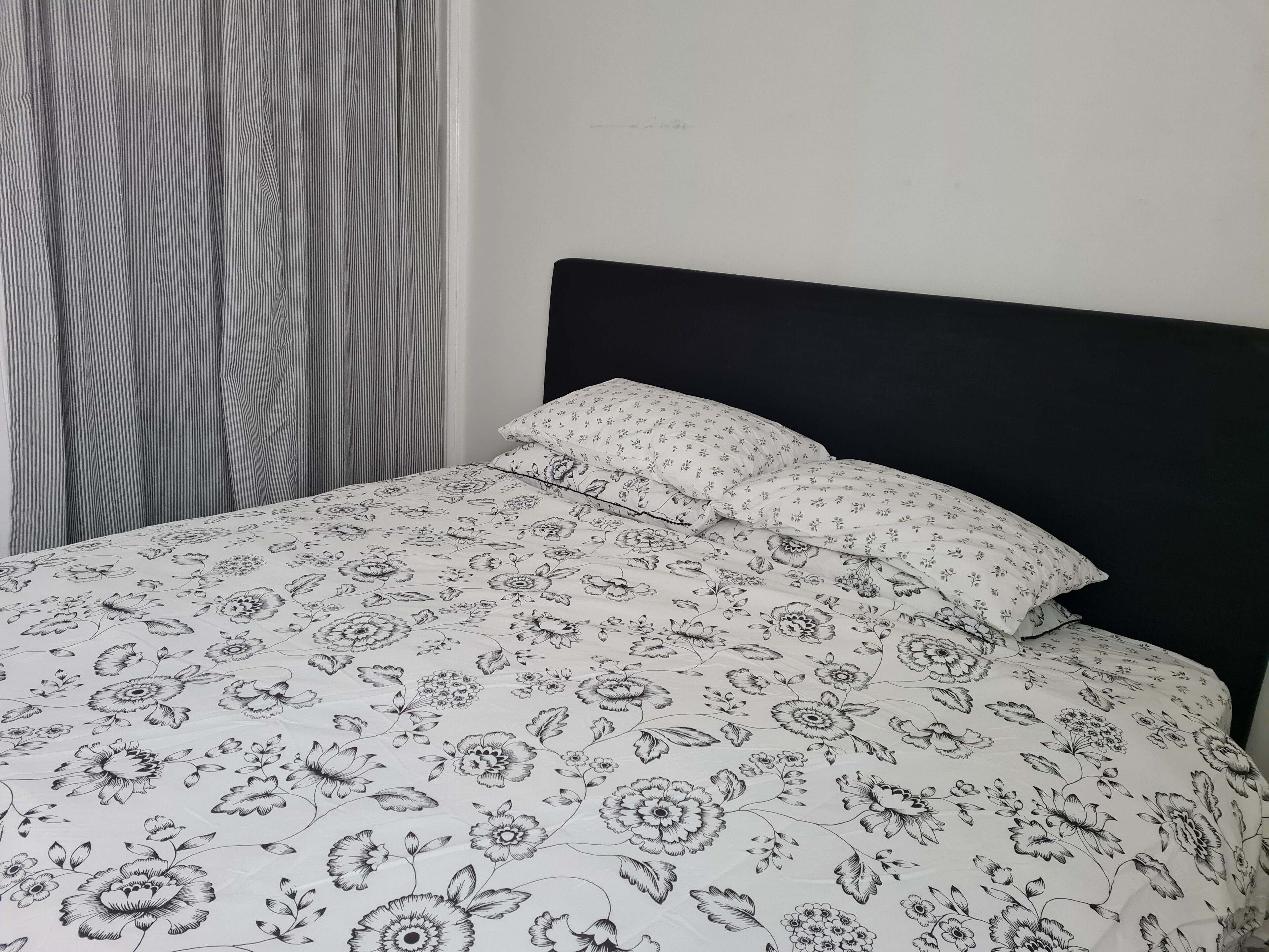 Un lit avec une couvre-lit à motifs floraux et une tête de lit noire.