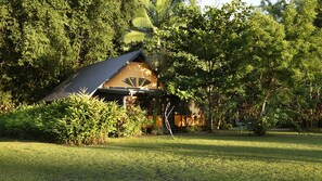A wooden cabin with a sloped roof surrounded by dense greenery.
