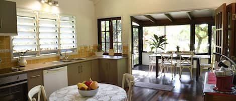 A kitchen with a dining area, a wooden floor, and a view through the open door.