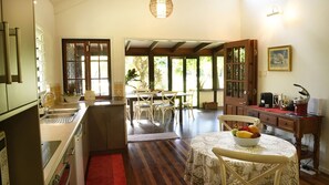 A spacious kitchen with a dining area, wooden cabinets, and a red rug.