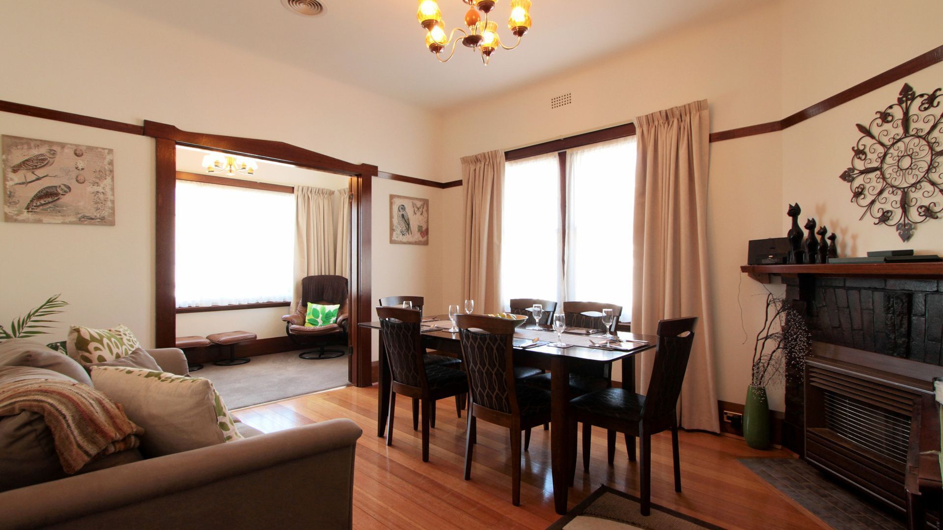 A dining area with a wooden table and chairs, a fireplace, and a view of the outdoors through large windows.