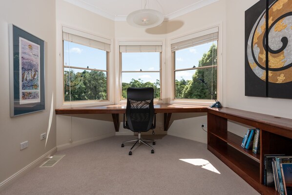 Un bureau d’angle avec un bureau, une chaise et une bibliothèque.