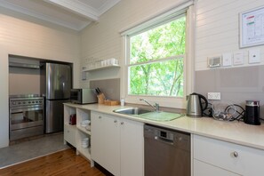 A modern kitchen with stainless steel appliances, a large window, and a view of greenery outside.