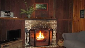 A cozy living room with a brick fireplace, a television, and a sofa. - Willow Cottage @ Hidden Valley Retreat Cottages (Grose Vale)