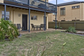 Un immeuble résidentiel doté d’un patio couvert, d’une cour arrière clôturée et d’un petit jardin.