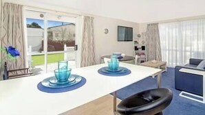 A hotel room with a dining area, a TV mounted on the wall, and a view of the outdoors through the window. - Garden Studio ~ Coromandel Apartments (Coromandel Township)