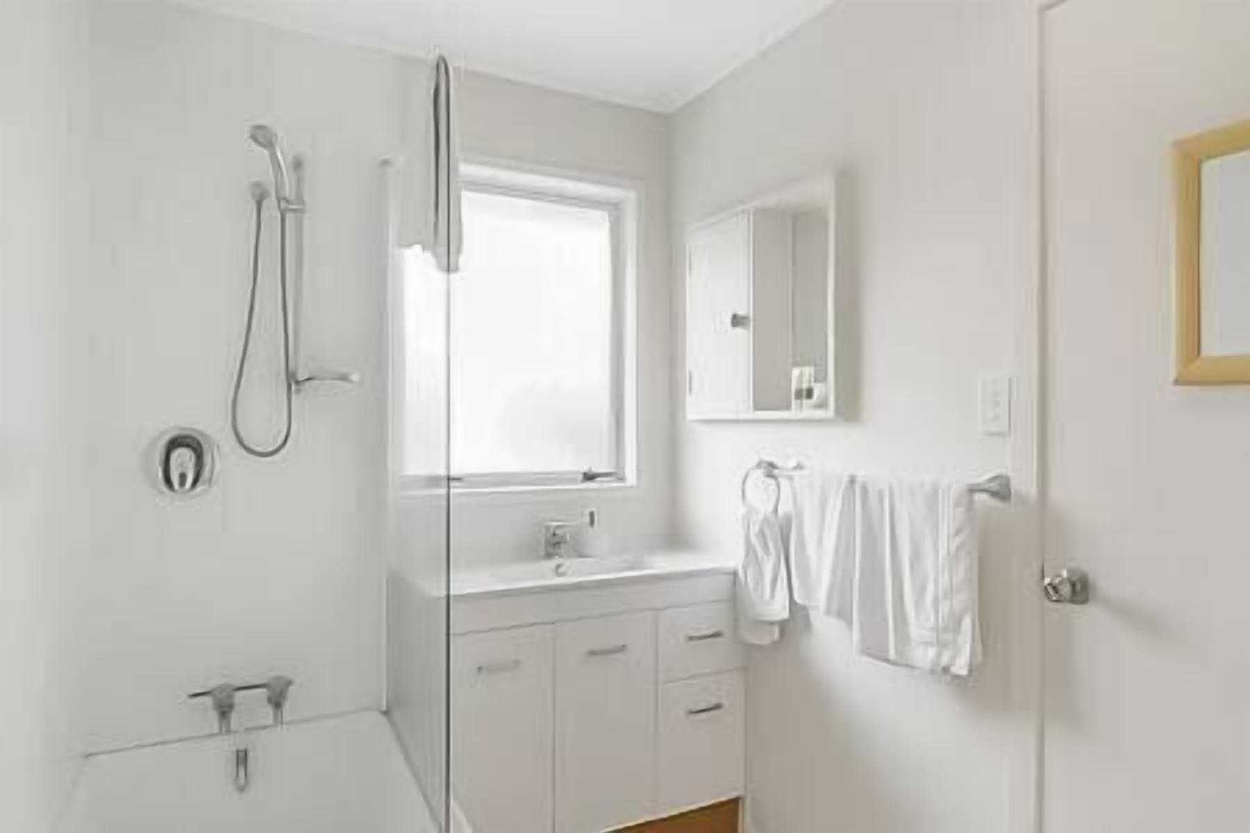 A modern bathroom with a shower, a sink, and a mirror.