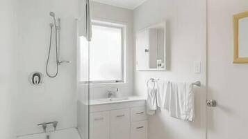 A modern bathroom with a shower, a sink, and a mirror.