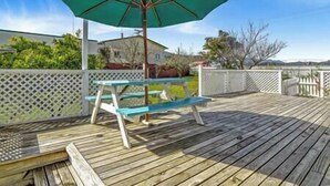 A wooden deck with a picnic table and a green umbrella. - Garden Studio ~ Coromandel Apartments (Coromandel Township)