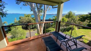 A balcony with a view of the sea and mountains, featuring a tiled floor and two lounge chairs. - COMPASS PT 5 - HAMILTON ISLAND - GREAT BARRIER REEF - WHITSUNDAYS - WHITEHAVEN (Hamilton Island)