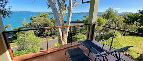 Un balcon offrant une vue sur la mer et les montagnes, doté d’un sol carrelé et de deux fauteuils.