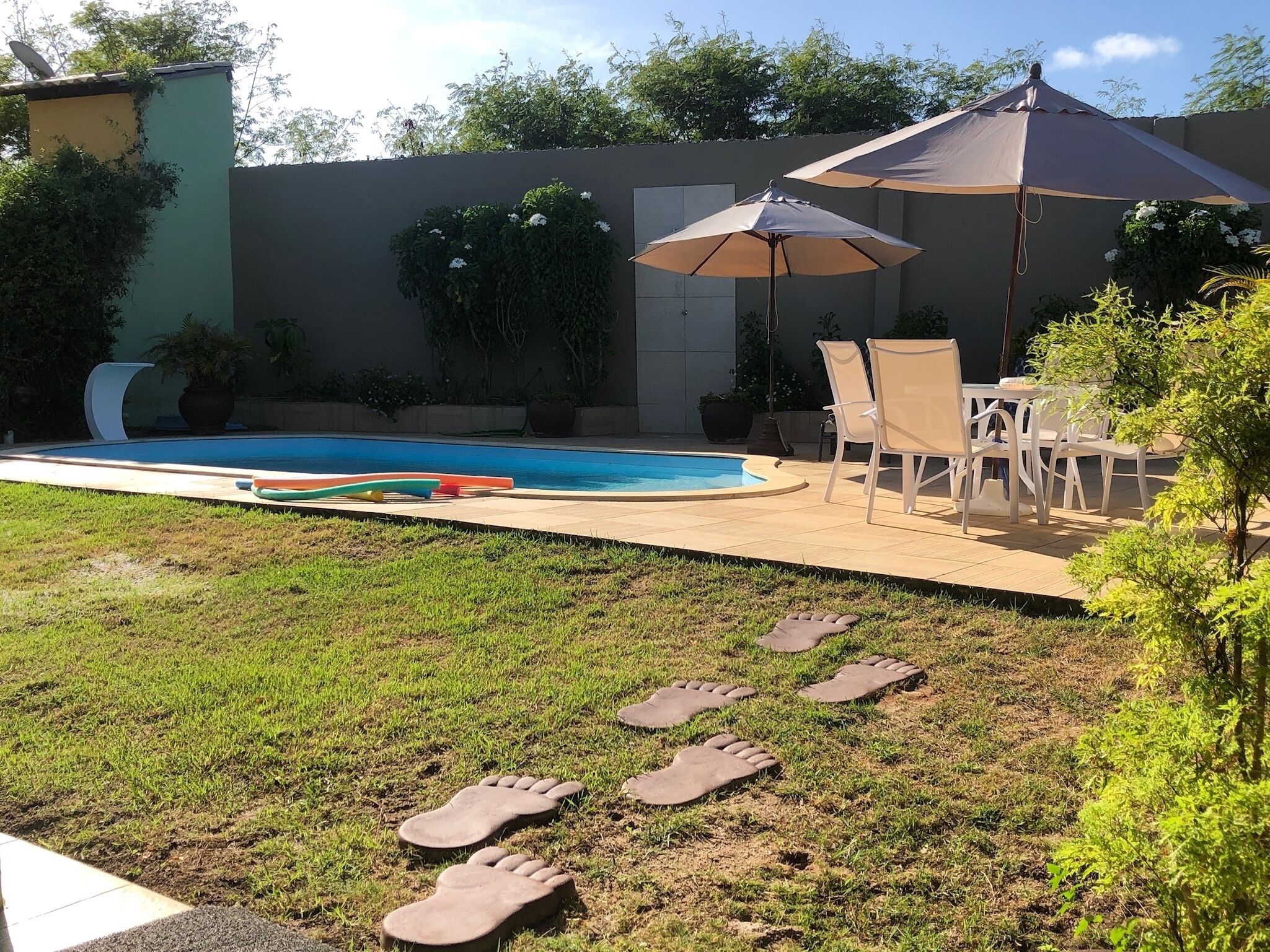 Ein Garten mit Swimmingpool, Gartenmöbeln und einer Grünfläche.