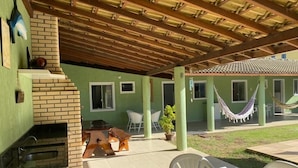 Un patio techado con chimenea de ladrillo, asientos exteriores y una hamaca.