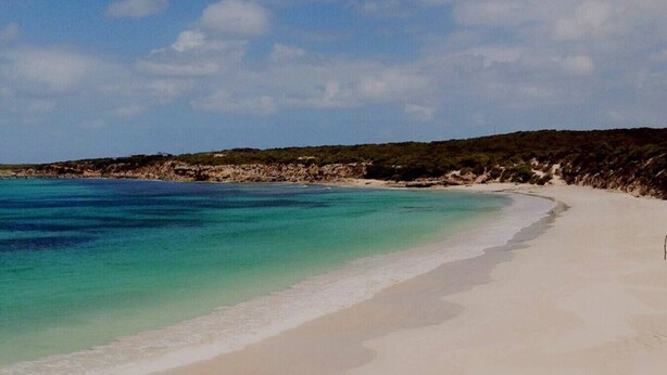 Una playa con aguas turquesas cristalinas y arena blanca.