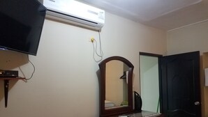 A room with a flat-screen TV, an air conditioner, a dresser with a mirror, a door, and a patterned chair. - HOLA SOY SERENA, MI PROPIEDAD  SE LLAMA  "CASA SERENA" (GUAYAQUIL)