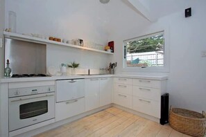 A kitchen with white cabinetry, a window, and a wooden floor.