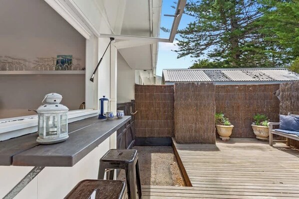 A wooden deck with a built-in bar area, potted plants, and a seating area. - Portsea Haven (Portsea)