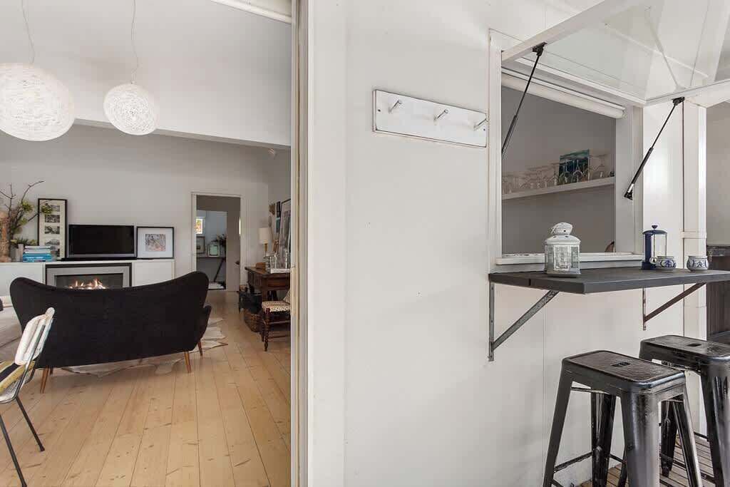 A modern kitchen with a black bar stool, a dining table, and a fireplace.