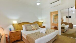 Ein Hotelzimmer mit einem großen Bett, Nachttischen, einem Spiegel und einem Kleiderschrank.