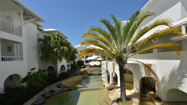 Ein Resort mit Pool, Palmen und weißen Gebäuden.