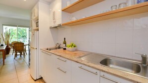 Eine moderne Küche mit weißen Schränken, einer Edelstahl-Spüle und Holzregalen.