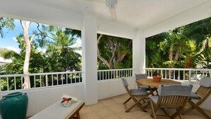 Eine überdachte Terrasse mit Tisch, Stühlen und einer Bank, sowie einer großen, grünen Vase.