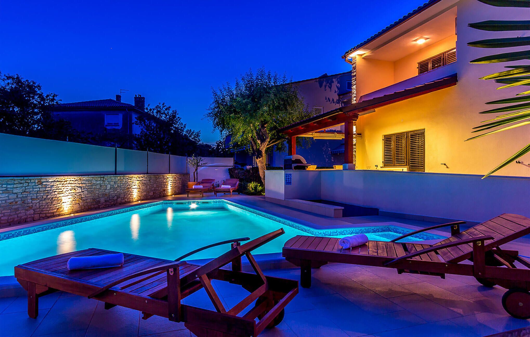 Ein Schwimmbecken mit Liegestühlen und einer überdachten Terrasse.