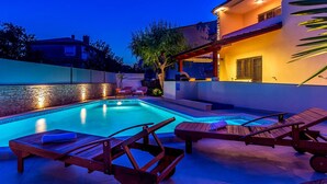 Ein Schwimmbecken mit Liegestühlen und einer überdachten Terrasse.