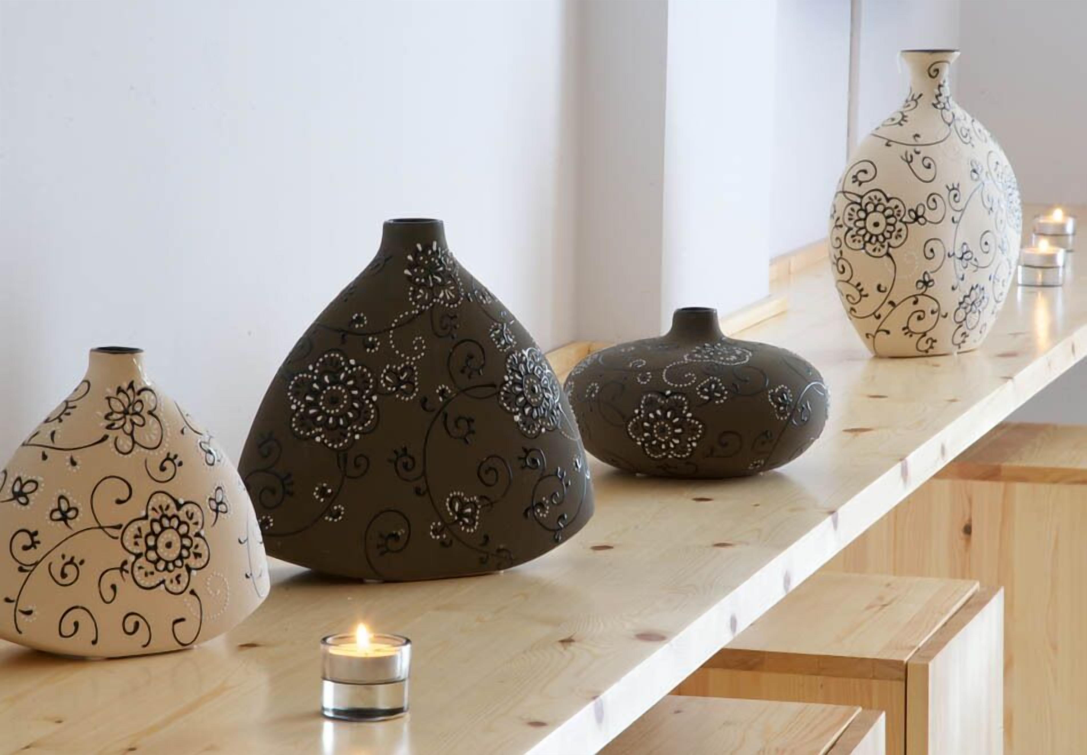 Four decorative vases with intricate patterns on a wooden shelf.
