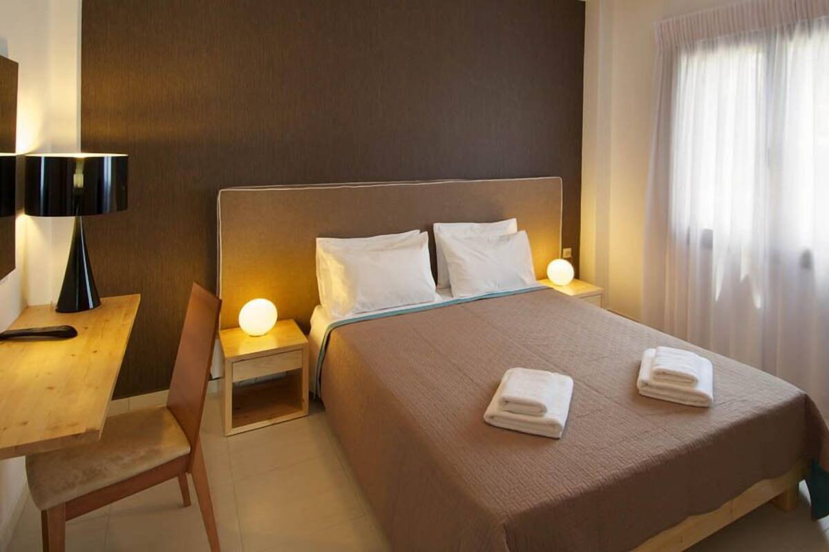 Une chambre d’hôtel avec un lit, des tables de chevet, un bureau et une chaise.