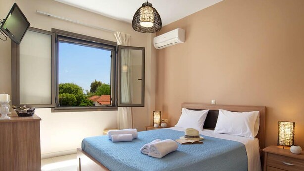 A hotel room with a large bed, bedside tables, a desk, and a window with curtains. - G Living 365 (Kefalonia)