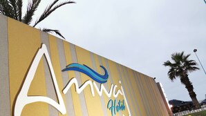 A hotel sign with a stylized wave design and the word "Hotel" in cursive. - Amwaj Hotel (El Jadida)