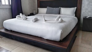 A neatly made bed with white linens and towels arranged in a swan shape. - Amwaj Hotel (El Jadida)