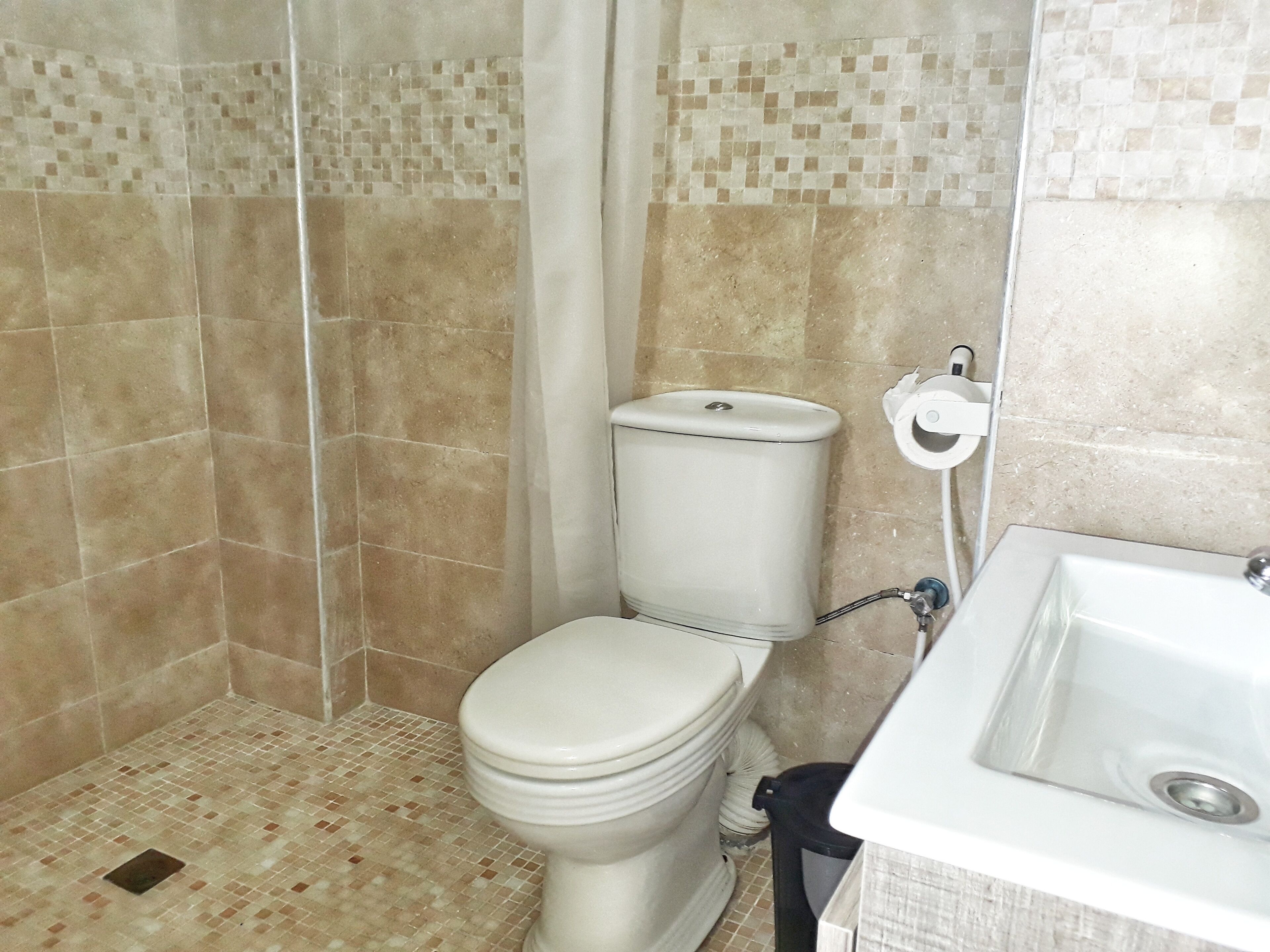 A bathroom with a toilet, a shower, and a sink.