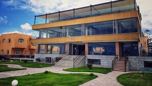 A modern building with a glass facade, a staircase leading to the entrance, and a well-maintained lawn area. - Amwaj Hotel (El Jadida)
