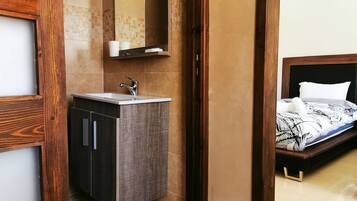 Un baño moderno con tocador de madera, un espejo grande y una cama con colcha estampada.