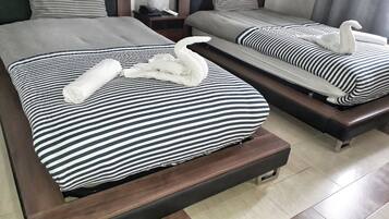 Habitación de hotel con dos camas, cada una con ropa de cama a rayas y una almohada con forma de cisne.