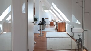 A modern interior with a wooden floor, a glass partition, and a kitchen area with a dining table and chairs. - Ferienwohnungen Ries (Eusserthal)
