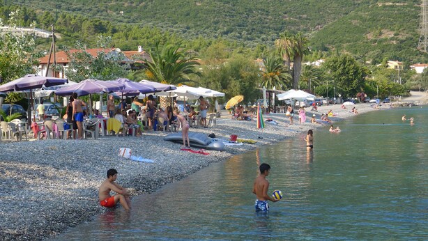 Una playa con gente, sombrillas y una masa de agua.